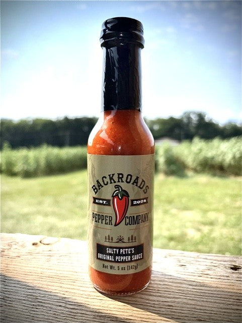 Salty Pete's Original Pepper Sauce bottle overlooking a pepper field