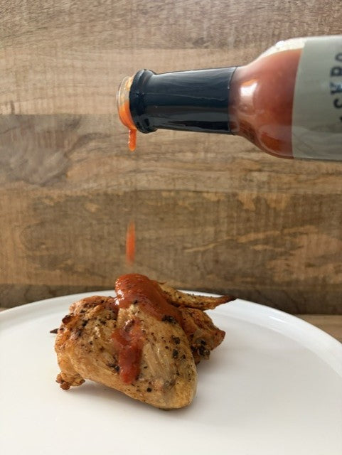 Salty Pete's Original Pepper Sauce being poured over grilled chicken